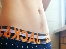 un chico con un cuerpo hermoso y una gran polla en bragas fuma en el balcón
